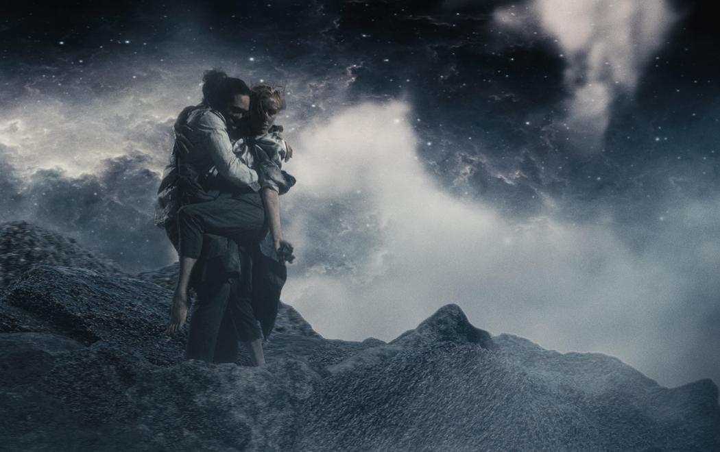A man carries a woman across a rocky, otherworldy landscape, surrounded by a dramatic night starscape..