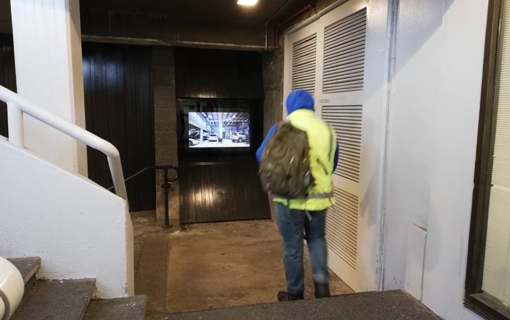 A worker in fluorescent vest watches a video installed in Masons Screen.
