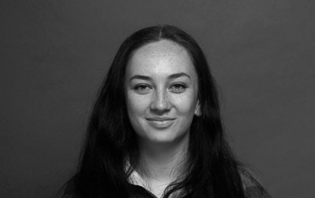 A young woman smiles at the camera. Her hair falls on her shoulders.
