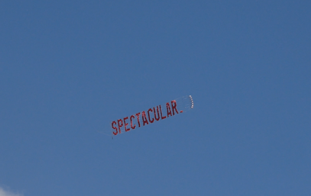 A red banner floating in blue sky reads 'spectacular'